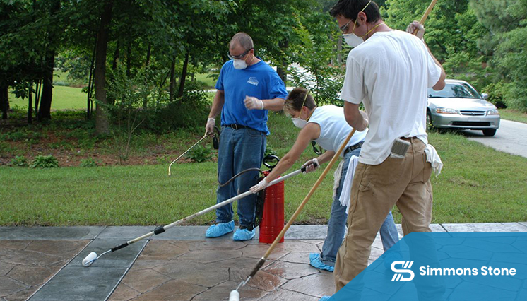 Professionals sealing a concrete patio with roller applicator