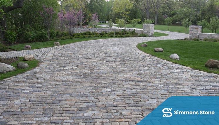 Stone paver driveway leading to a home’s front entry with custom inlays