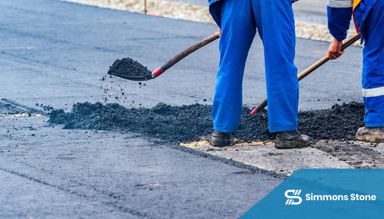 Worker applying patching material to asphalt driveway cracks