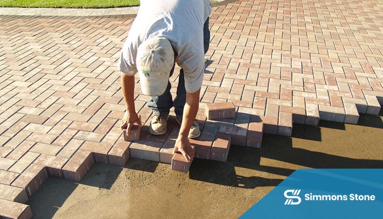 Crew re-installing paver block in a damaged driveway