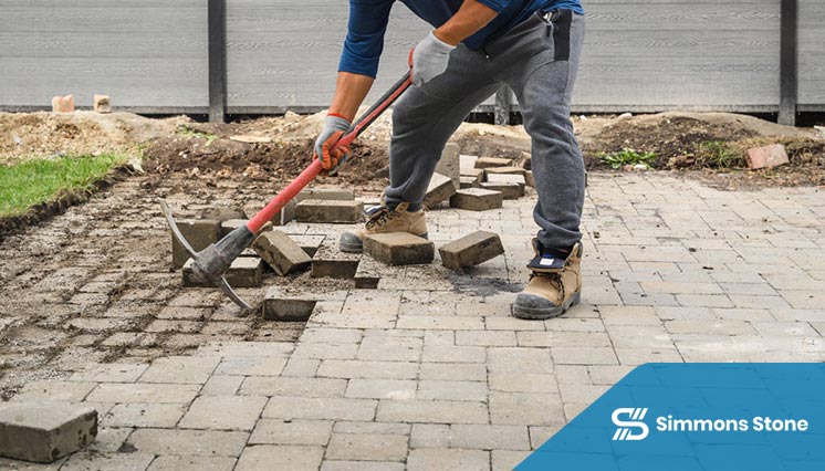 Crew repairing cracked and sunken pavers in a residential driveway